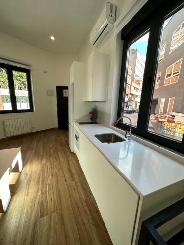 a kitchen with a white counter top and two windows at Apartamentos Bravo Murillo in Madrid