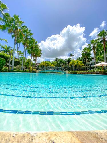 a large swimming pool with palm trees in the background at Xeliter Balcones del Atlantico - Las Terrenas in Las Terrenas