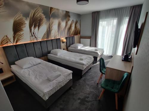 a hotel room with two beds and a desk at Nowe M4 Żyrardów Centrum - blisko Suntago in Żyrardów