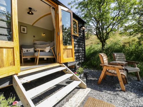 an open door of a tiny house with a chair at Moelfre - Shepherds Hut in Llanbedr