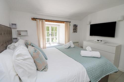 a bedroom with a white bed and a television at 2 Rose Cottages in St. Agnes 