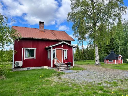 a red house with a red roof in a field at Kodikas Mökki in Ähtäri