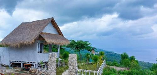 una piccola casa con un tetto di paglia su una collina di Ocean Glamping Penida a Nusa Penida