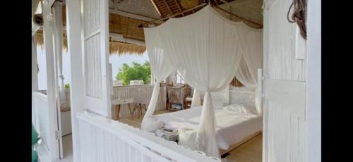 a bedroom with a white bed with a canopy at Ocean Glamping Penida in Nusa Penida