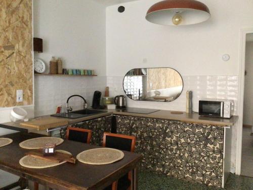 - une cuisine avec une table, un évier et un miroir dans l'établissement Appartement au coeur du village pour deux personnes, à Lespignan
