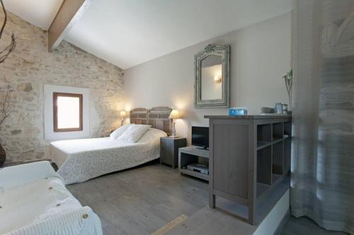 1 dormitorio con cama y espejo en Mas de village avec piscine et grand jardin clôturé, en Fournès