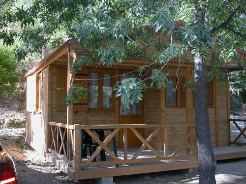 a log cabin with a porch and a tree at Camping El Balcon de Pitres in Pitres