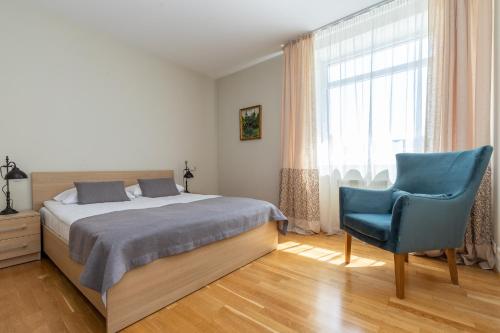 a bedroom with a bed and a blue chair at CAMELIA CENTRE APARTMENT in Palanga