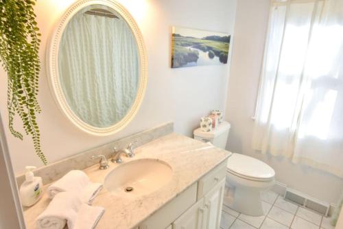 La salle de bains est pourvue d'un lavabo, d'un miroir et de toilettes. dans l'établissement Stunning Bay Views by Beach Dog Friendly, à Eastham