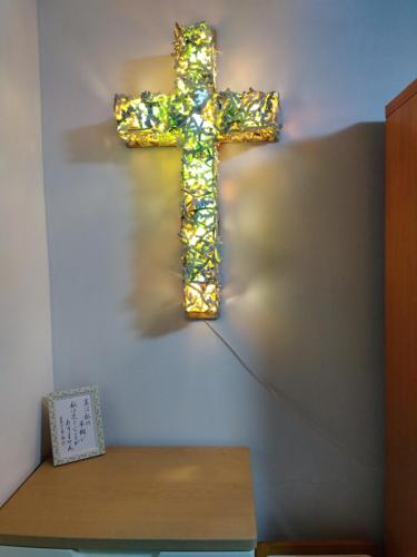 a cross hanging on a wall next to a table at Miyagi Apartment Tomari in Naha