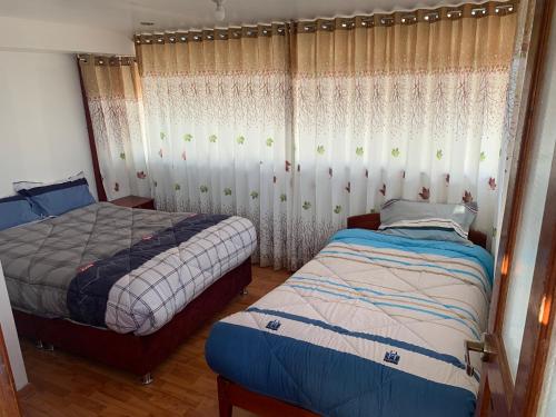 a bedroom with two beds and a window with curtains at Summit Viewpoint House San Blas in Cusco