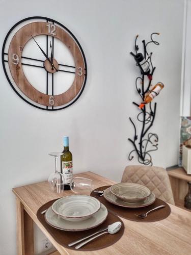 a clock hanging on a wall above a table with plates at Apartman Mikeš in Sombor