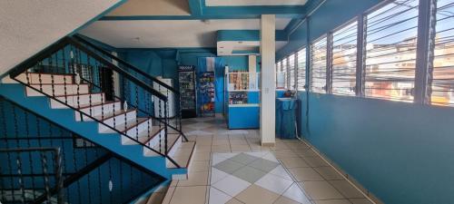 Un escalier se trouve dans un bâtiment doté de murs et de fenêtres bleus. dans l'établissement Hotel Los Andes Tegucigalpa, à Tegucigalpa