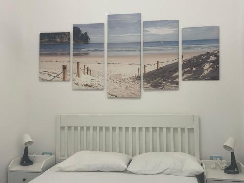Zimmer mit einem Bett und fünf Gemälden eines Strandes in der Unterkunft Villa Margherita in Vieste