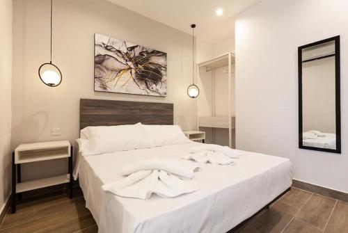 a white bed in a bedroom with two lights at Studio 21 with kitchenette at the new Olo living in Paceville