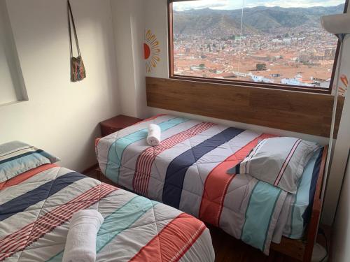 a room with two beds and a window with a view at Summit Viewpoint House San Blas in Cusco