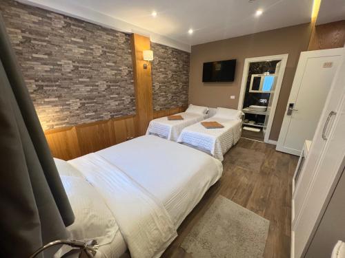 a bedroom with two beds and a brick wall at Hotel Romeo in Korçë