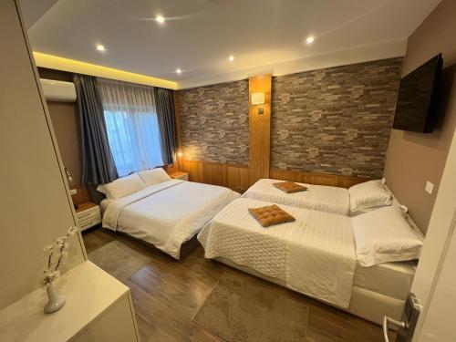 a bedroom with two beds and a brick wall at Hotel Romeo in Korçë