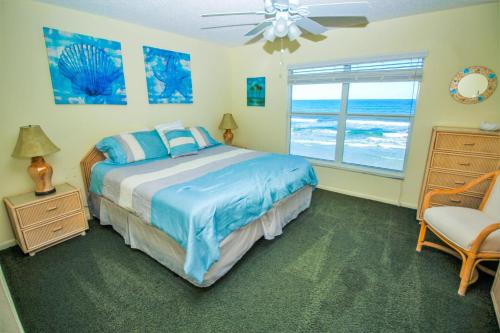 a bedroom with a bed and a window and a chair at Sea Coast Gardens III 303 in New Smyrna Beach