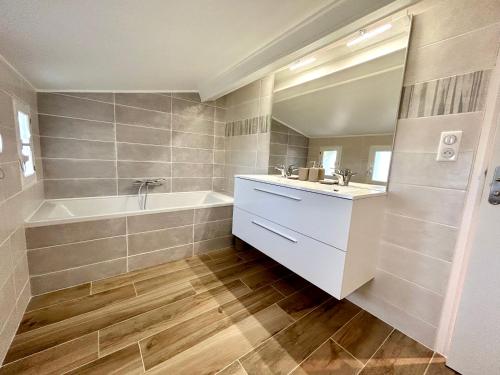 a bathroom with a tub and a sink and a bath tubermott at Gite de La Rastelle au coeur de la nature in Savignac-de-Duras