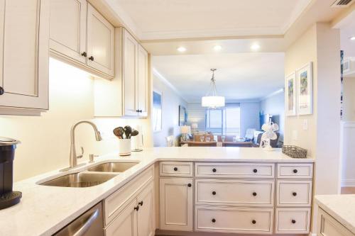 uma cozinha com armários brancos e um lavatório em Sea Coast Gardens II 105 em New Smyrna Beach