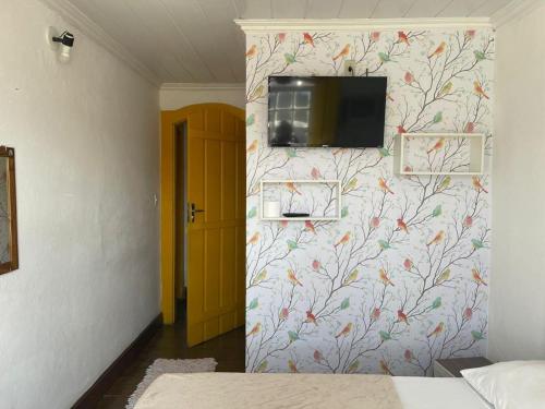 a bedroom with a wall with a tv on a wall at Pousada Fortaleza in Paraty