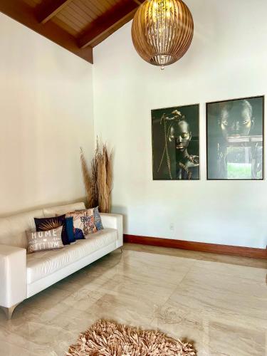 a living room with a white couch and pictures on the wall at Lara's Home Suites in Capitólio