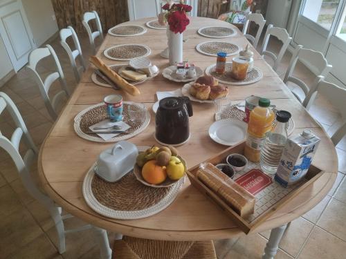 a wooden table with breakfast foods on it at Chambres d'hôtes Le Petit Gravier in La Chapelle-aux-Choux