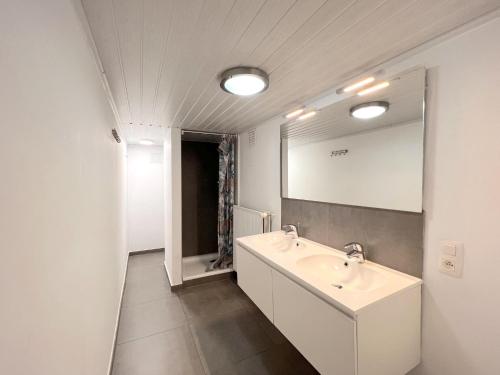 ein weißes Badezimmer mit einem Waschbecken und einem Spiegel in der Unterkunft Devant les Thiers in Lierneux