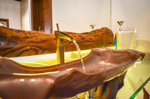 a copper sink with water coming out of it at Lara's Home Suites in Capitólio