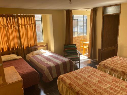 um quarto de hotel com duas camas e uma cadeira em CAYESH Guest House em Huaraz