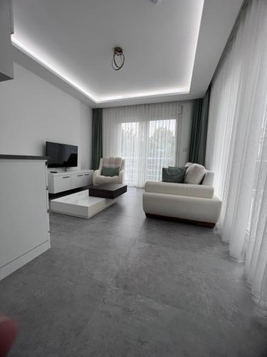 Luna Alacati في ألاتشاتي: غرفة معيشة بها كنبتين بيضاء وتلفزيون