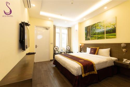 a bedroom with a large bed and a painting on the wall at Suji My Dinh Hotel in Hanoi