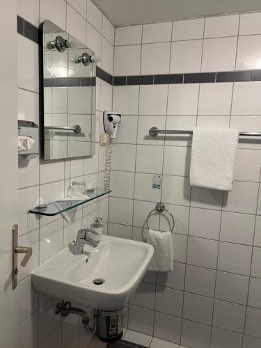 a white bathroom with a sink and a mirror at Hotel Schwartzer Löwe in Babenhausen