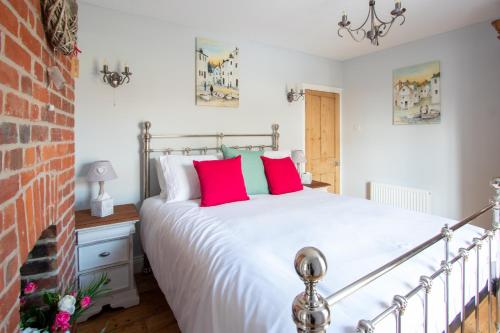 a bedroom with a large white bed with red pillows at Stylish Town Centre House with Garden and Parking Opposite in Bury Saint Edmunds