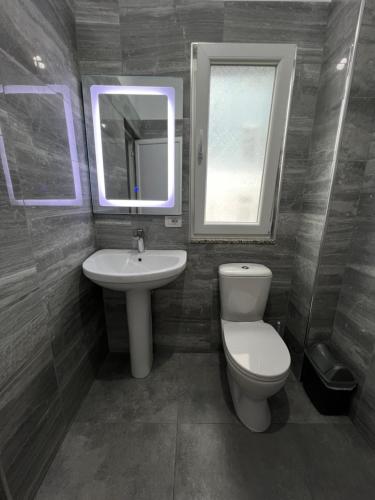 a bathroom with a toilet and a sink and a mirror at Vila Kledi in Shëngjin