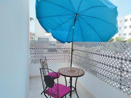 a table and chairs with a blue umbrella on a balcony at Your Airport Oasis Resort 15 Minutes from Rabat in Salé