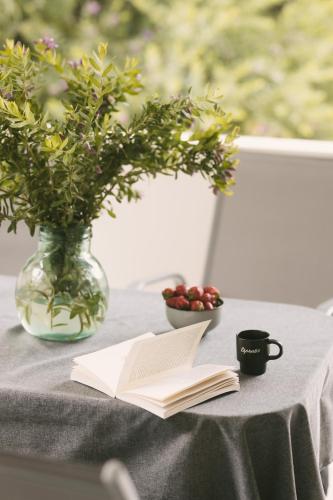 a table with a book and a vase of flowers and a cup of coffee at Grey House in Chorafakia