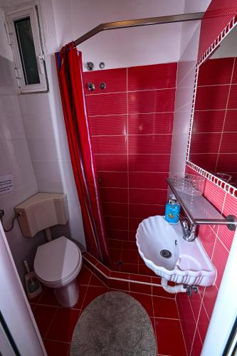 a red bathroom with a sink and a toilet at Four Seasons 1 in Paralia Katerinis