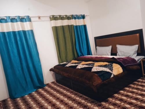 a bedroom with two beds with blue curtains at Nubra Holiday in Deskit