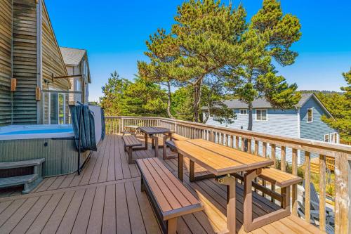 a deck with picnic tables and a hot tub at Cape Escape in Pacific City