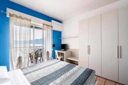 a bedroom with blue walls and a bed and a desk at Residence Casa e Vela in Oggebbio