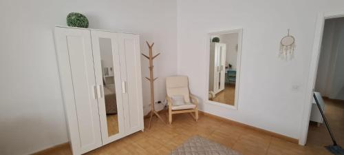 een witte kamer met een stoel en een spiegel bij Piso de 2 habitaciones a 200 metros de la playa in Las Palmas de Gran Canaria