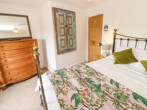 a bedroom with a bed with a wooden dresser and a mirror at Old Wool Shop in Leyburn