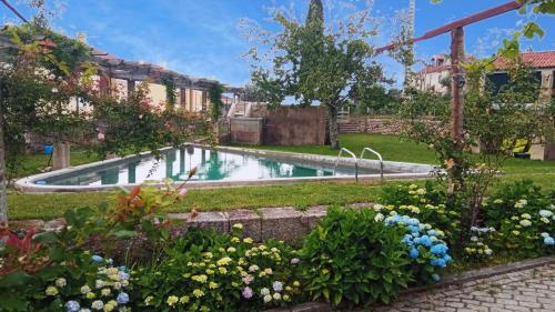 a swimming pool in a yard with flowers at Casa de Santa Bárbara - Cinfães in Cinfães