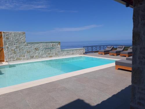 a swimming pool with chairs and the ocean in the background at Argileos Rooms in Himare