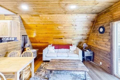Copper Top Chalet في ليفنوورث: غرفة معيشة مع أريكة بيضاء وجدران خشبية