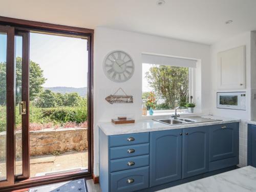 a kitchen with a sink and a clock on the wall at Bryn Llifon in Pentraeth