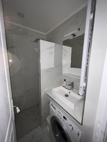 La salle de bains blanche est pourvue d'un lavabo et d'un lave-linge. dans l'établissement Cosy appartement paris à deux pas, à Courbevoie