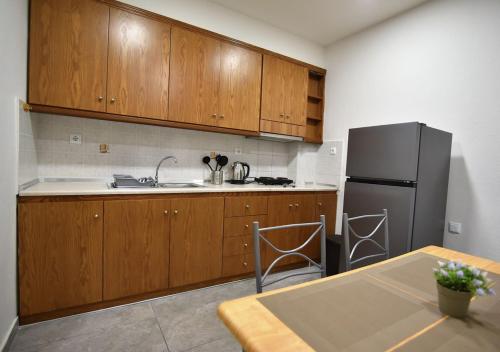 a kitchen with wooden cabinets and a black refrigerator at Villa Vayia in Stavros